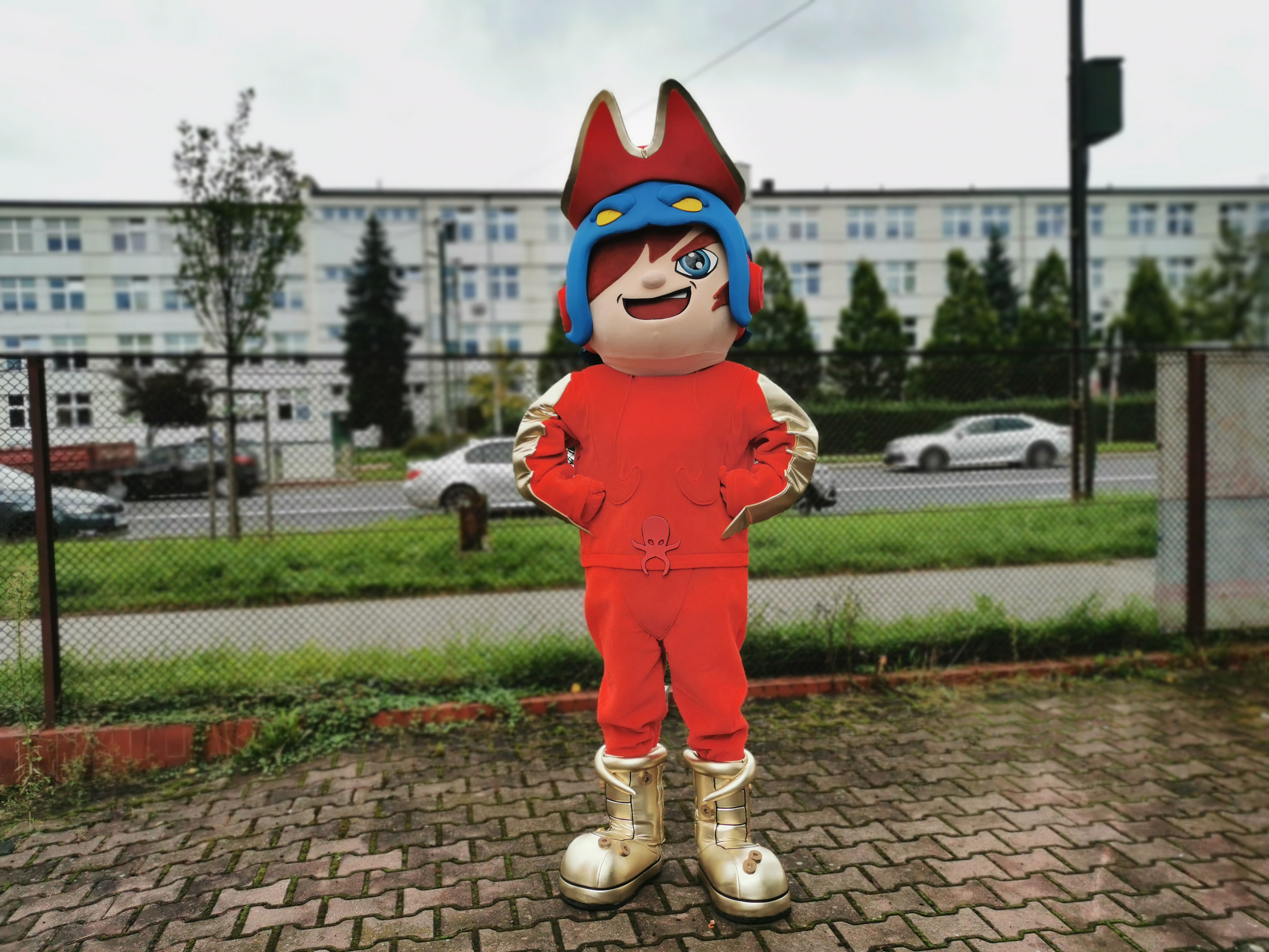Na fotografii widnieje przebranie w postaci figurki Golden Kraken z kolekcji T-Racers pozujące do zdjęcia opodal siedziby firmy Elabika